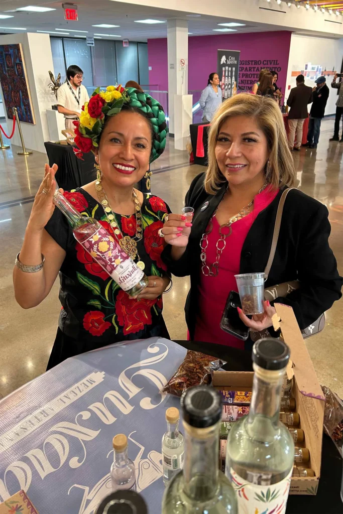 Guxadi mezcal tasting at a cultural event—traditional attire, authentic products.