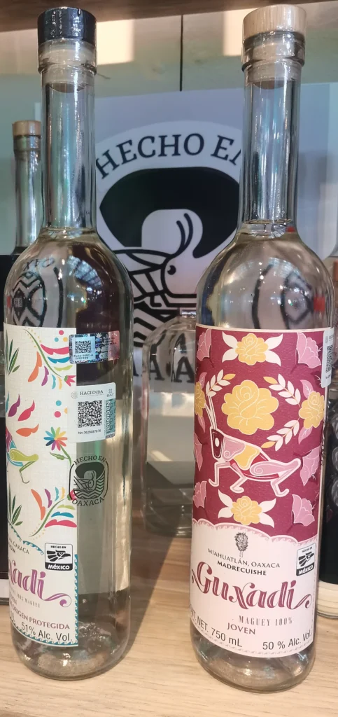 Deux bouteilles de mezcal Guxadi 750 ml avec le sceau d’Appellation d’Origine (DO) et les mentions « Hecho en México / Hecho en Oaxaca ».